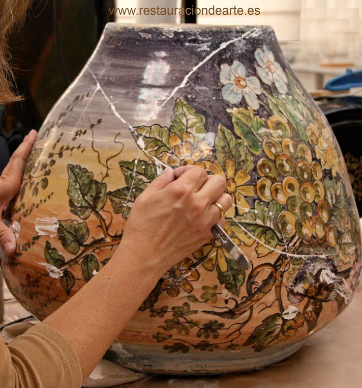 restauración de vasija en barro cocido policromada y vidriada, restauradora en proceso de reintegración de la pequeñas perdidas después de la adhesión de fragmentos