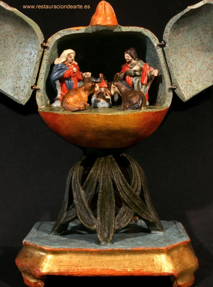 Fotografía final de la granada en barro cocido y policromado con las puertas abiertas donde deja ver el pequeño nacimiento formado por San José, la Virgen y el niño Jesús, acompañados del buey y la mula, después de la restauración.
