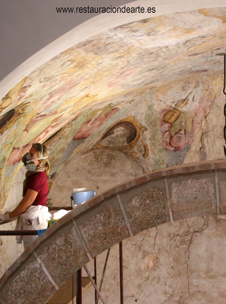 Proceso de limpieza de la película pictórica y mortero durante la restauración de la pintura mural, realizado por restauradora de pintura
