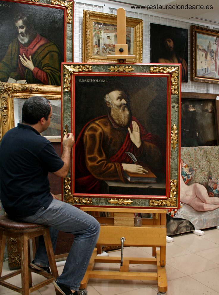 Restaurador en el estudio de pintura, durante el proceso de restauración de un cuadro y marco barroco