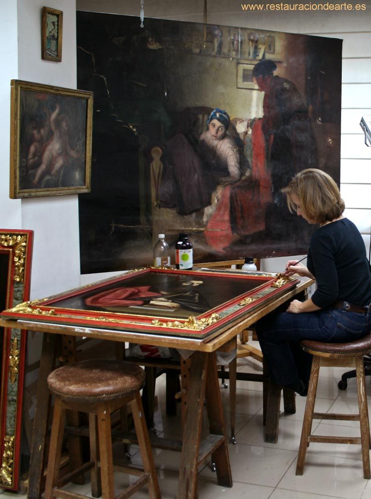 Restauradora en el estudio de pintura en Madrid, durante el proceso de restauración de un cuadro y marco